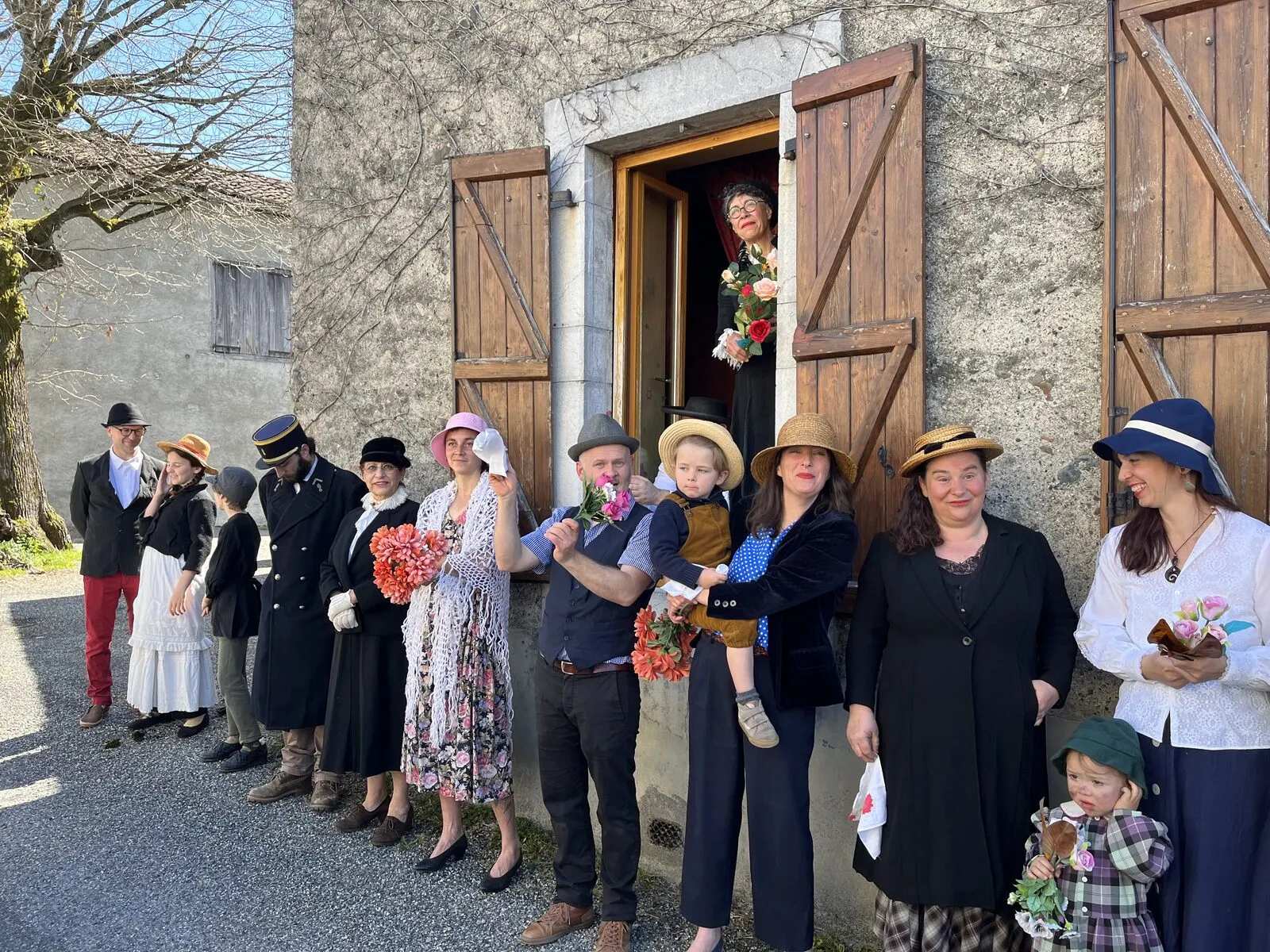 Une dizaine de comédien·nes en costumes des années 1920 devant la porte du Café