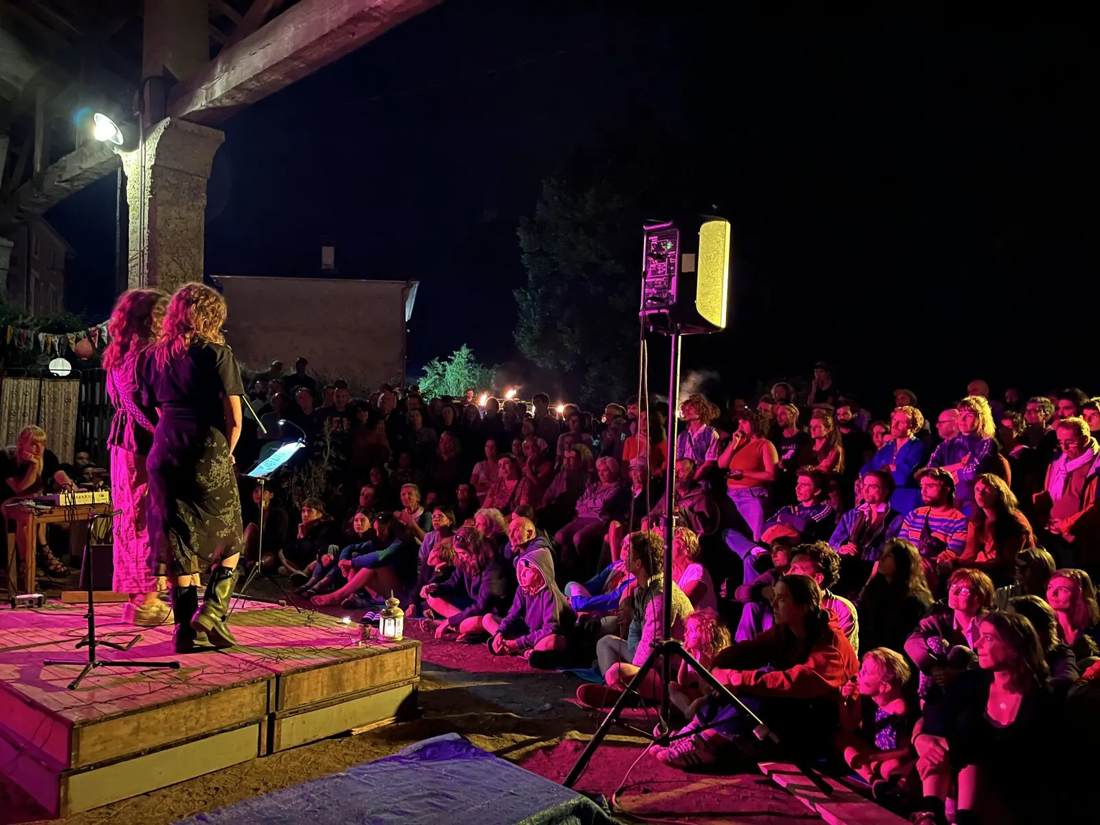 Concert de nuit sur la scène extérieure, public assis par terre